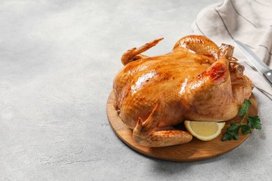 Tasty roasted chicken with parsley and lemon on light grey table. Space for text