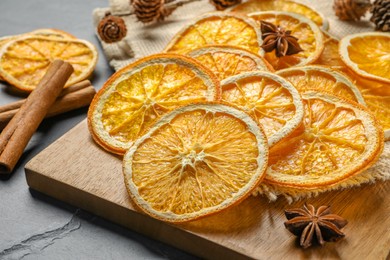 Photo of Many dry orange slices and spices on black textured table, closeup