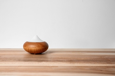 Photo of Aroma oil diffuser lamp on table against light background