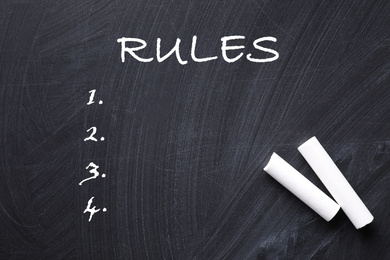 Image of White chalk sticks on blackboard with list of rules, flat lay