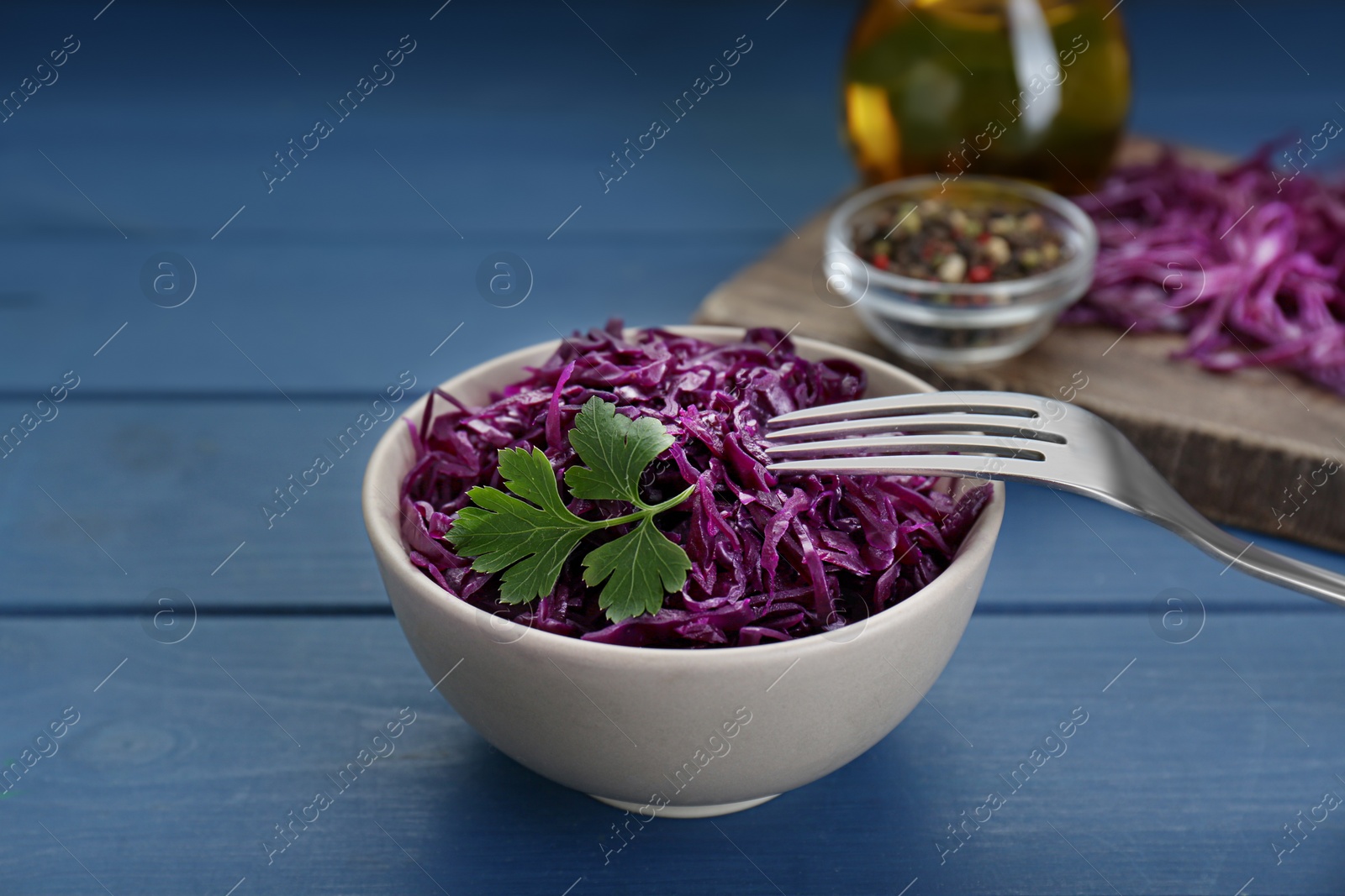 Photo of Tasty red cabbage sauerkraut with parsley on light blue wooden table