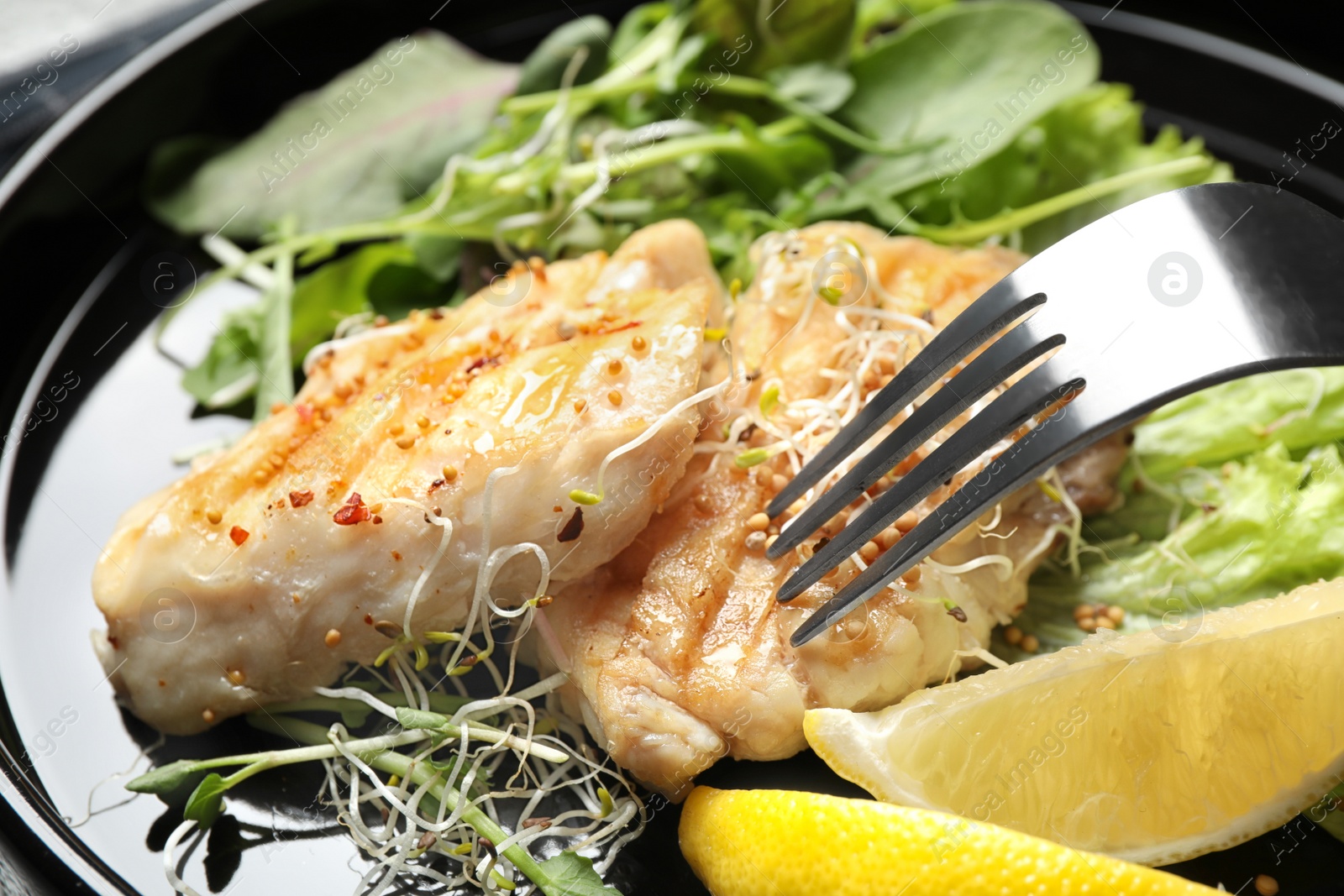 Photo of Tasty grilled fish with lemon on plate, closeup