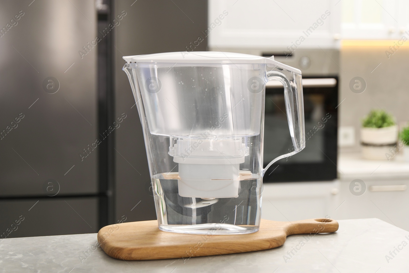 Photo of Water filter jug on light table in kitchen, closeup