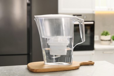 Photo of Water filter jug on light table in kitchen, closeup