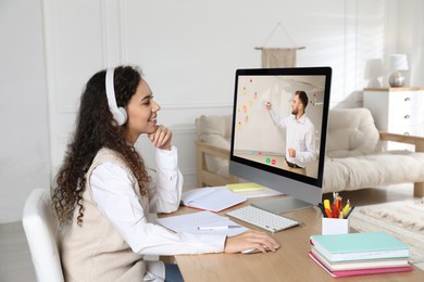Image of E-learning. Young woman having online lesson with teacher via computer at home