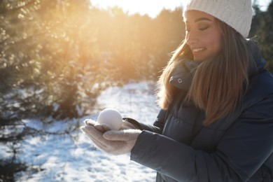 Photo of Woman holding snowball outdoors on winter day, space for text