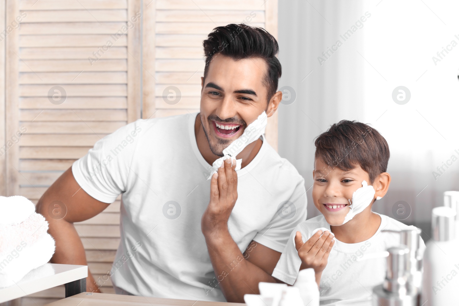 Photo of Father and son having fun while shaving in bathroom