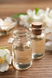 Photo of Jasmine essential oil and fresh flowers on wooden table