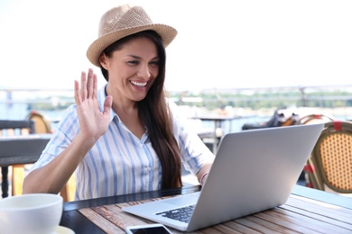 Photo of Beautiful woman using laptop at outdoor cafe
