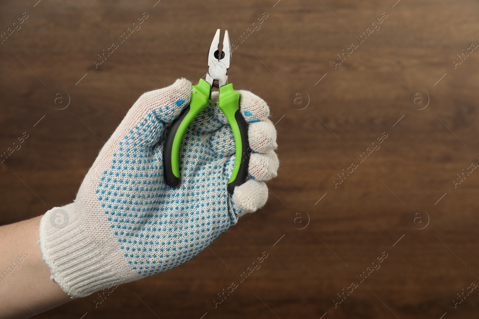 Photo of Man with combination pliers on wooden background, closeup. Space for text