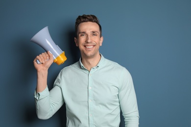 Photo of Young man with megaphone on color background