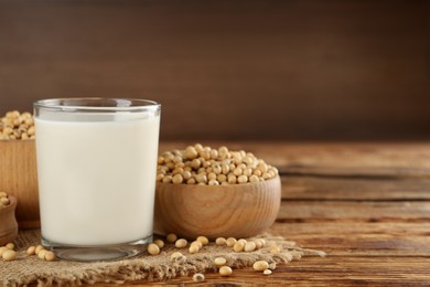 Photo of Glass with fresh soy milk and grains on wooden table. Space for text