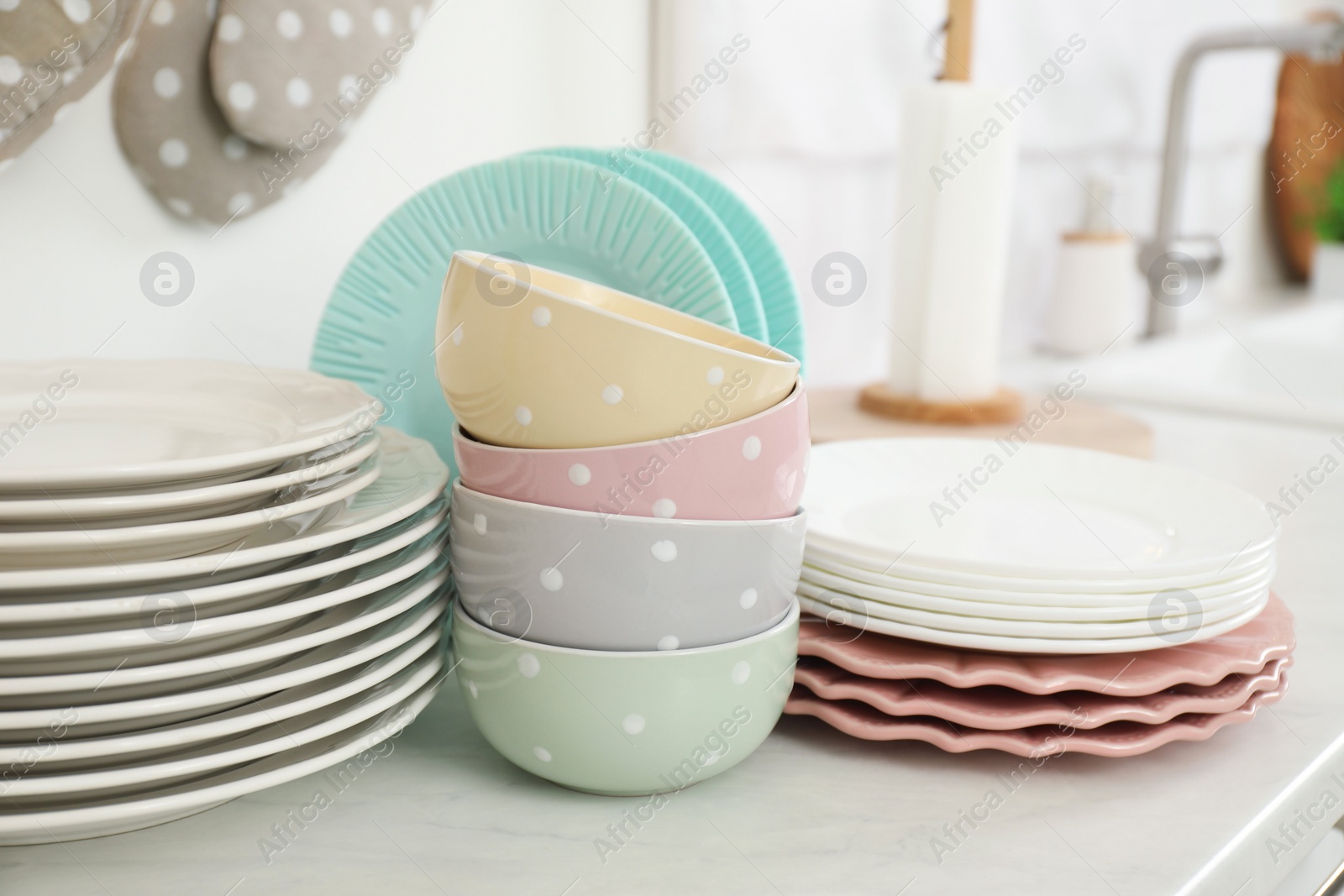 Photo of Clean plates and bowls on white marble countertop in kitchen