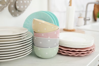 Clean plates and bowls on white marble countertop in kitchen