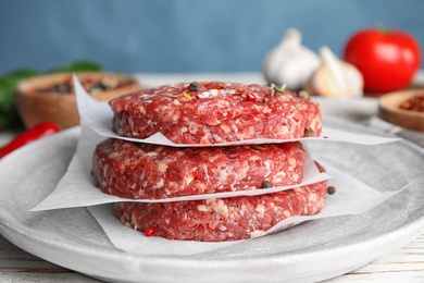 Photo of Raw meat cutlets for burger on white wooden table, closeup
