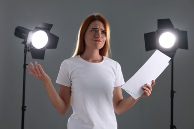 Casting call. Emotional woman with script performing on grey background in studio