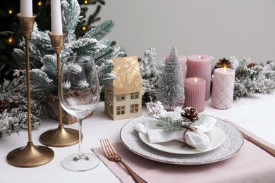 Festive place setting with beautiful dishware, cutlery and cone for Christmas dinner on white wooden table