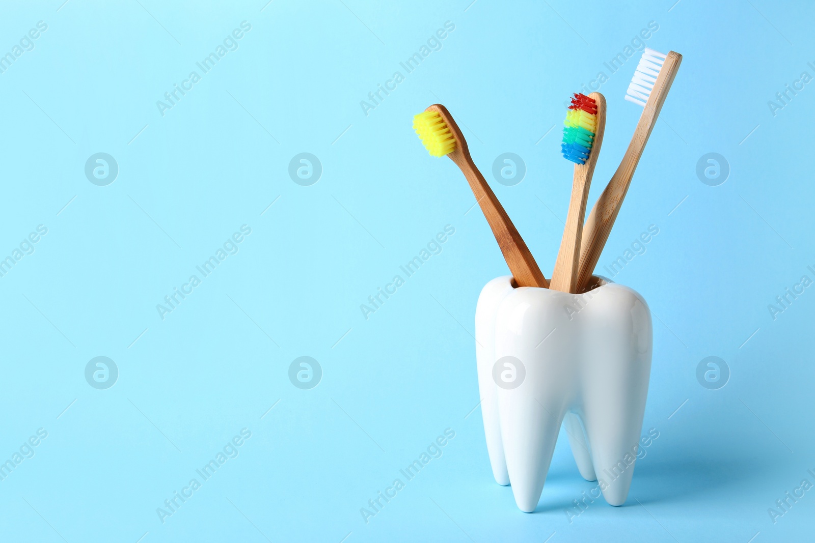 Photo of Tooth shaped holder with brushes on color background. Space for text