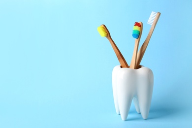 Tooth shaped holder with brushes on color background. Space for text