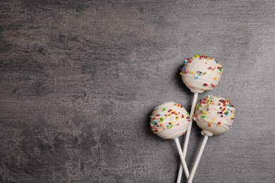 Bright delicious cake pops on dark background, flat lay. Space for text