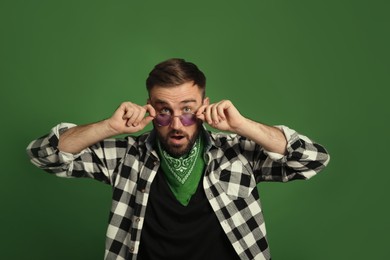 Photo of Fashionable young man in stylish outfit with bandana on green background