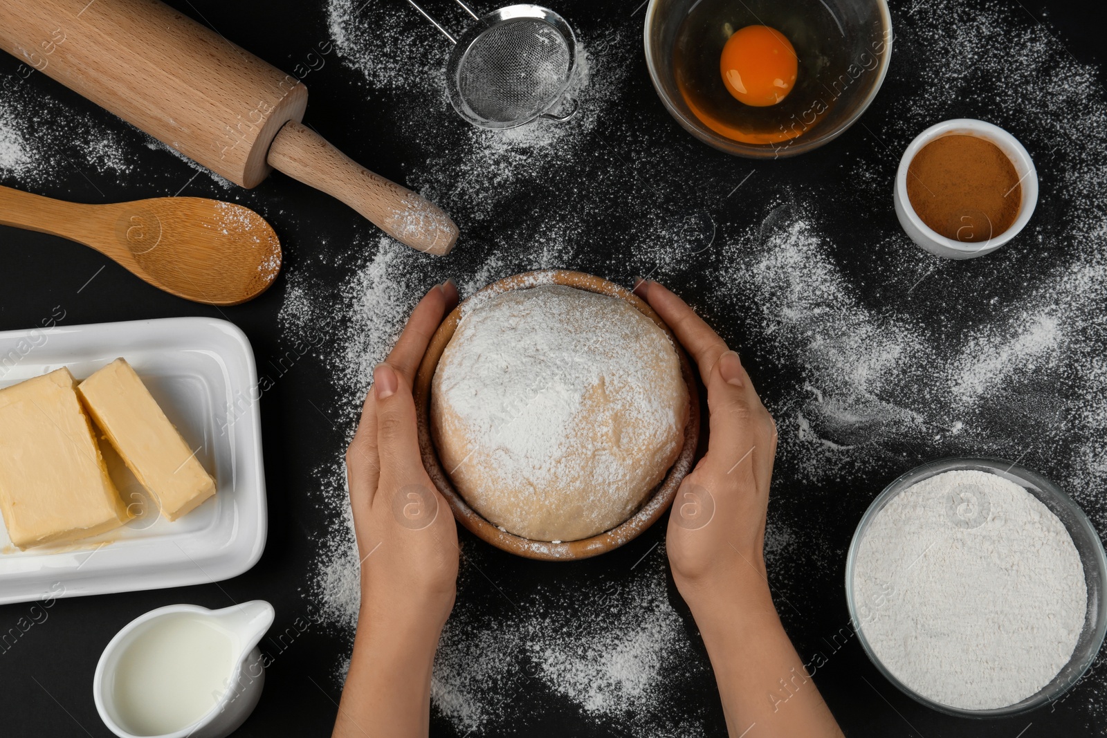 Photo of Woman with fresh dough at black table, top view. Baking pie