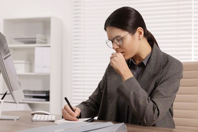 Photo of Woman coughing while taking notes at table in office, space for text. Cold symptoms