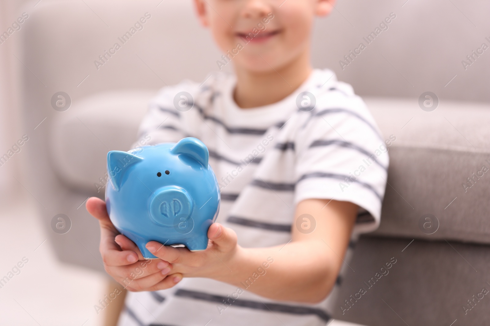 Photo of Little boy with piggy bank at home, closeup