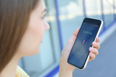 Photo of Woman using voice search on smartphone outdoors, closeup