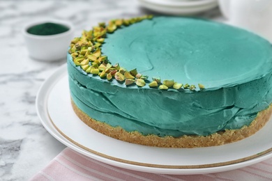 Photo of Delicious homemade spirulina cheesecake decorated with pistachios on marble table