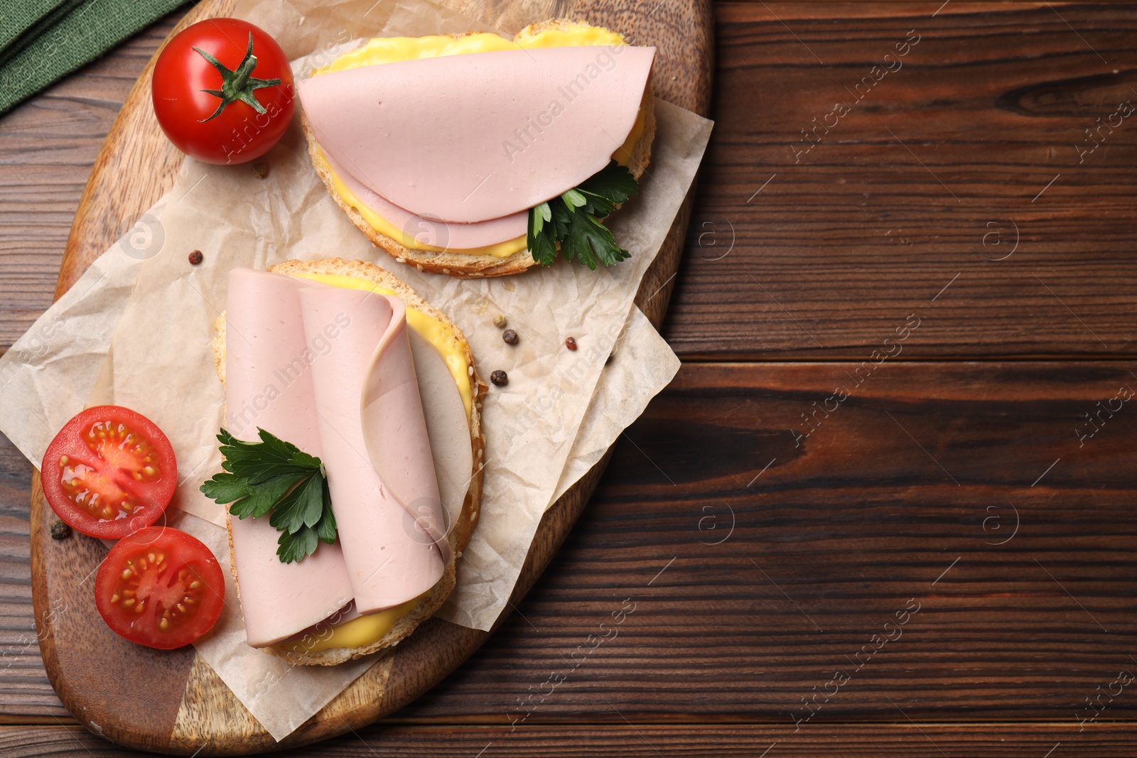 Photo of Delicious sandwiches with boiled sausage, cheese and tomatoes on wooden table, top view. Space for text