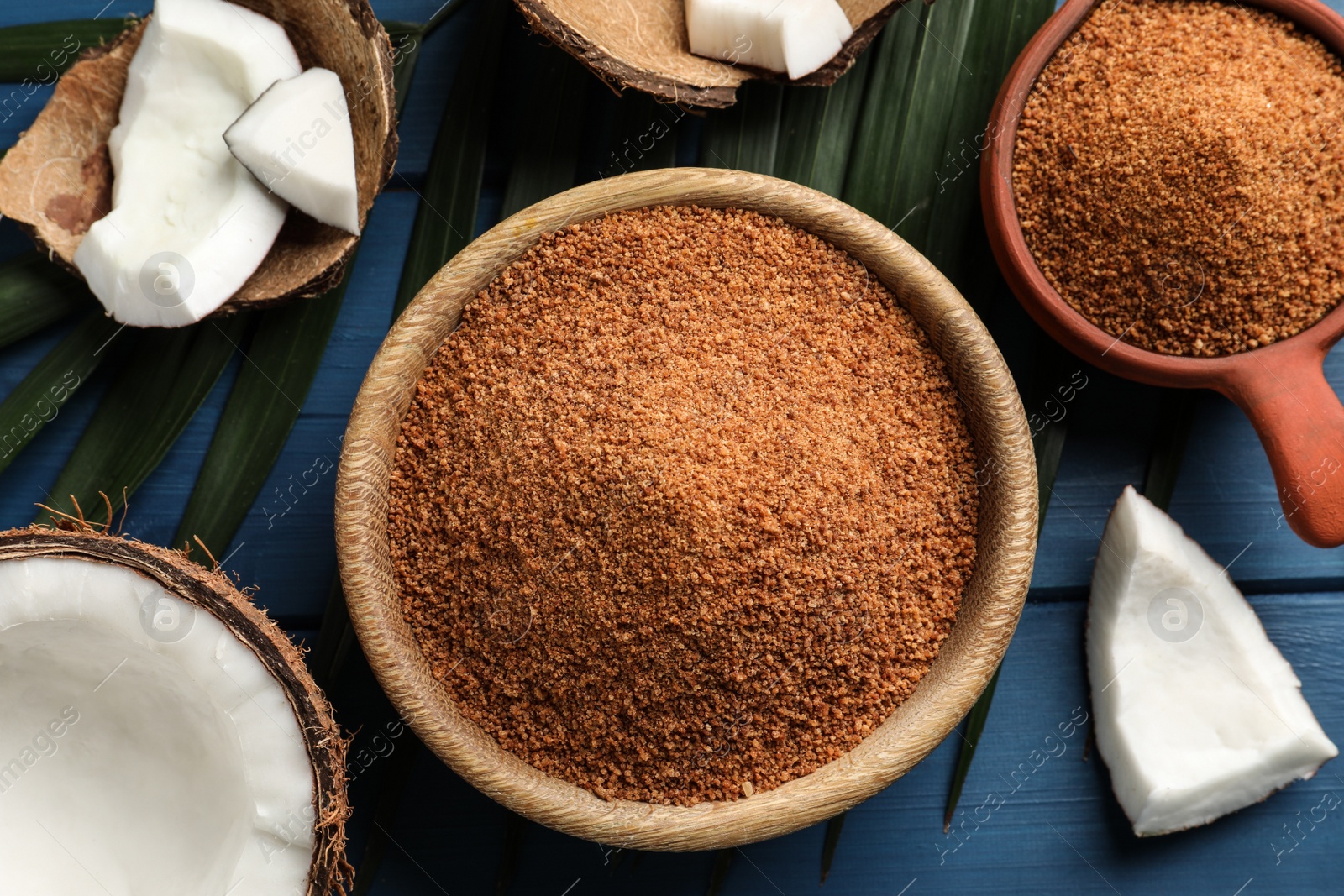 Photo of Flat lay composition with natural coconut sugar on blue wooden table