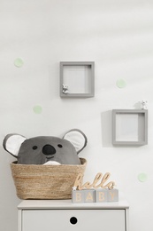 Wooden cubes and wicker basket on chest of drawers indoors. Children's room interior