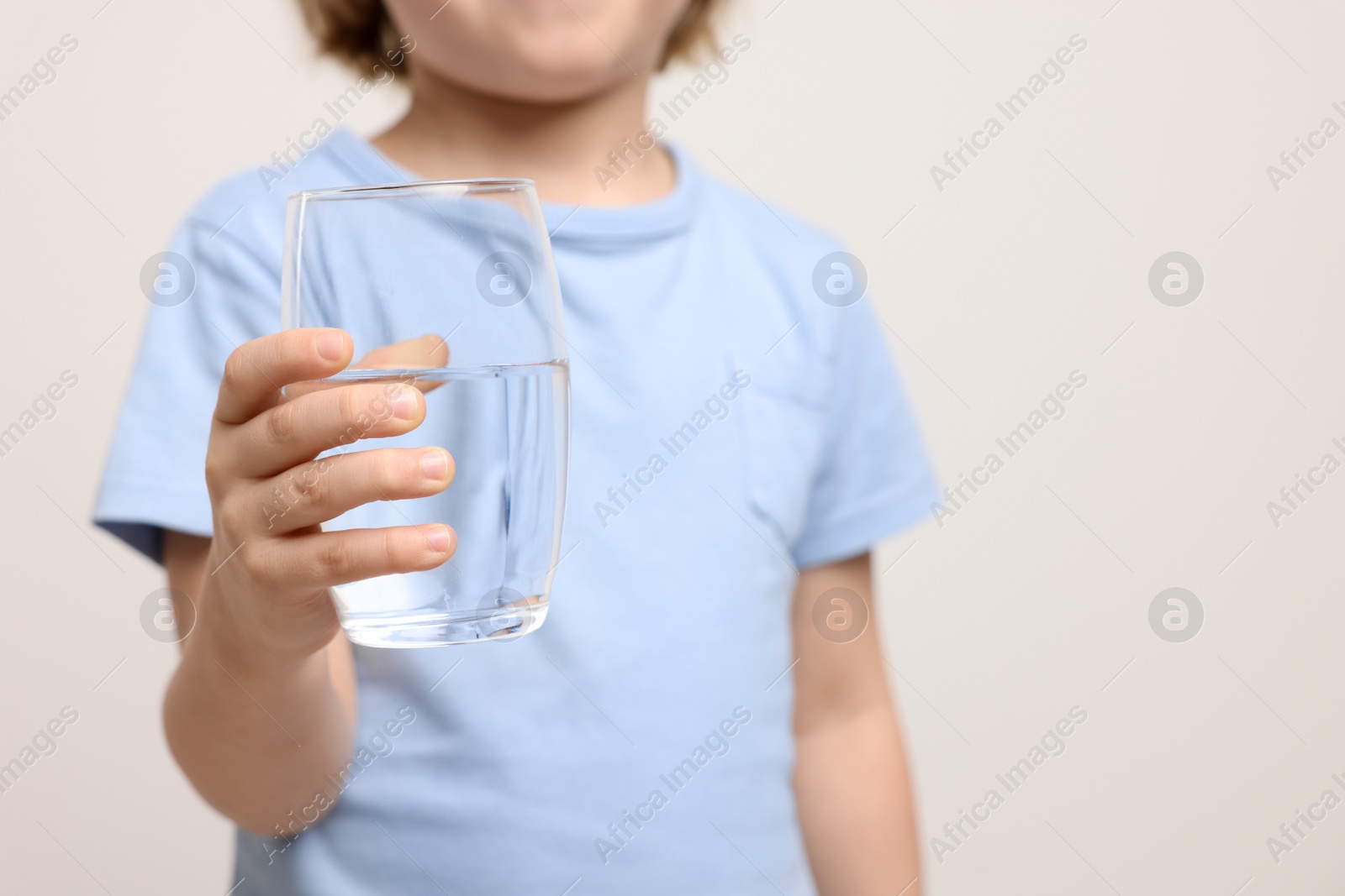 Photo of Little boy holding glass of fresh water on white background, closeup. Space for text