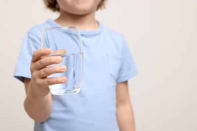 Photo of Little boy holding glass of fresh water on white background, closeup. Space for text