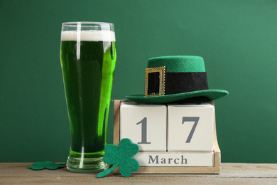 Photo of Composition with green beer and clover leaves on wooden table. St. Patrick's Day celebration