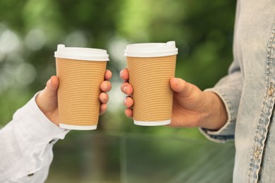 Women holding takeaway paper cups outdoors, closeup. Coffee to go