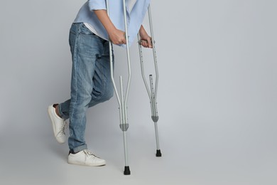 Photo of Man with injured leg using crutches on grey background, closeup. Space for text