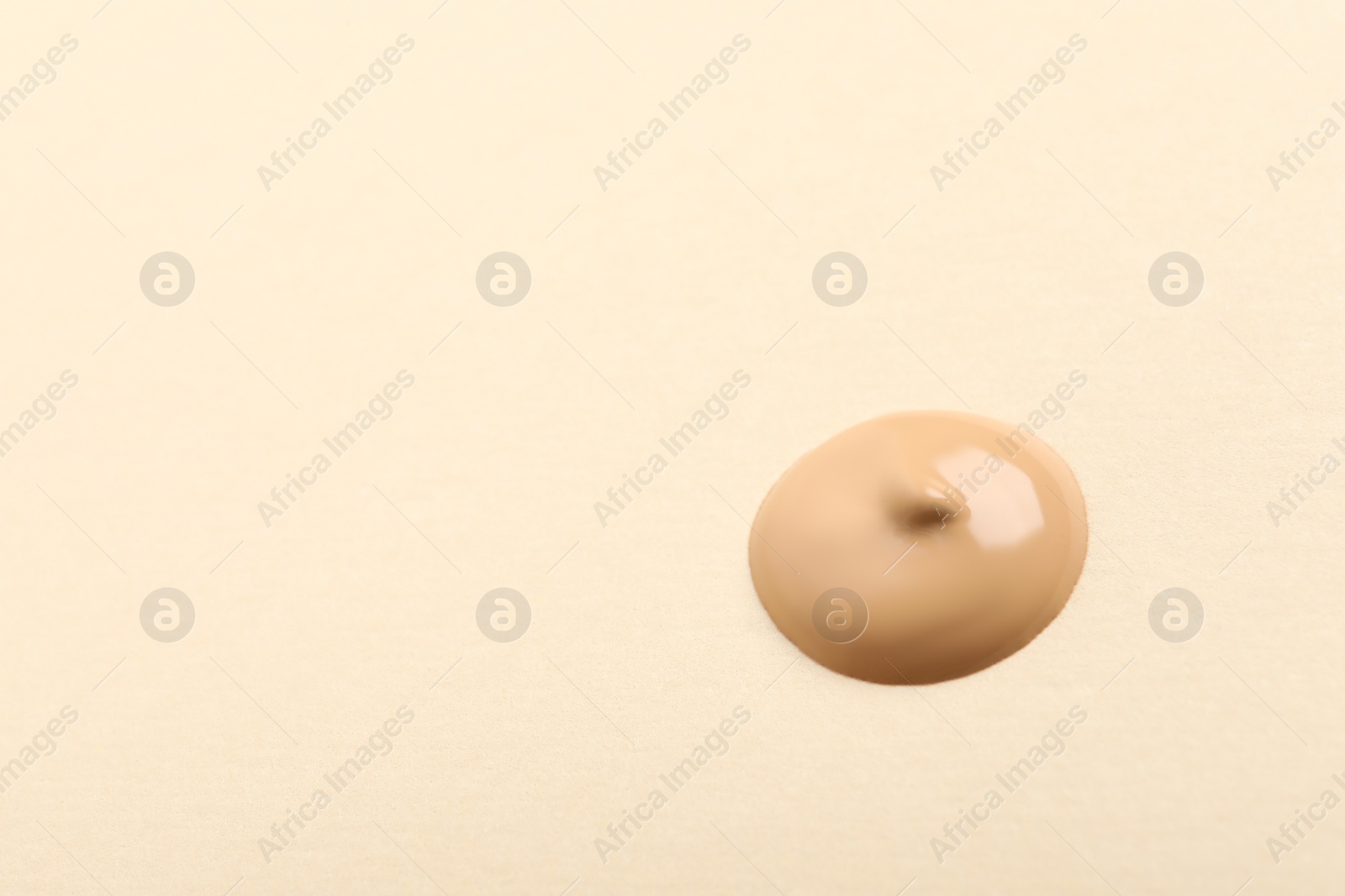 Photo of Drop of skin foundation on beige background. Space for text