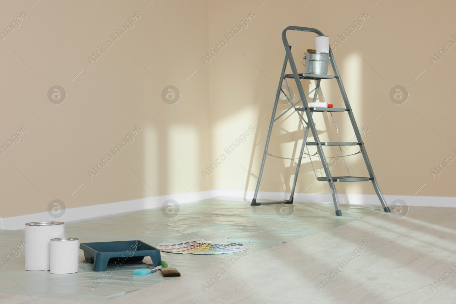 Photo of Stepladder and painting tools near wall in empty room, space for text