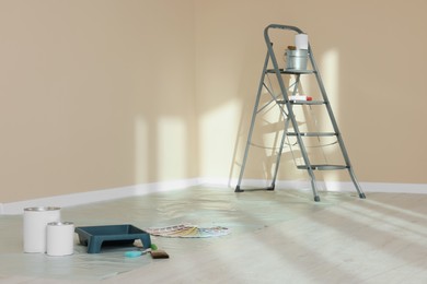 Stepladder and painting tools near wall in empty room, space for text