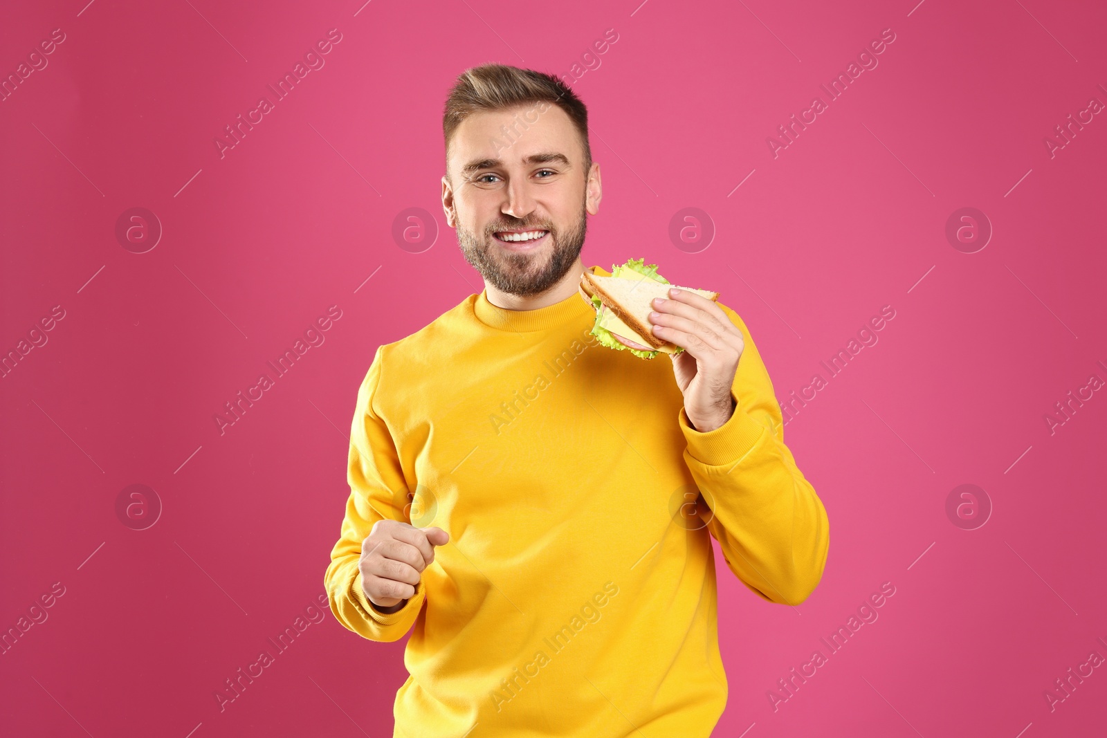 Photo of Young man with tasty sandwich on pink background