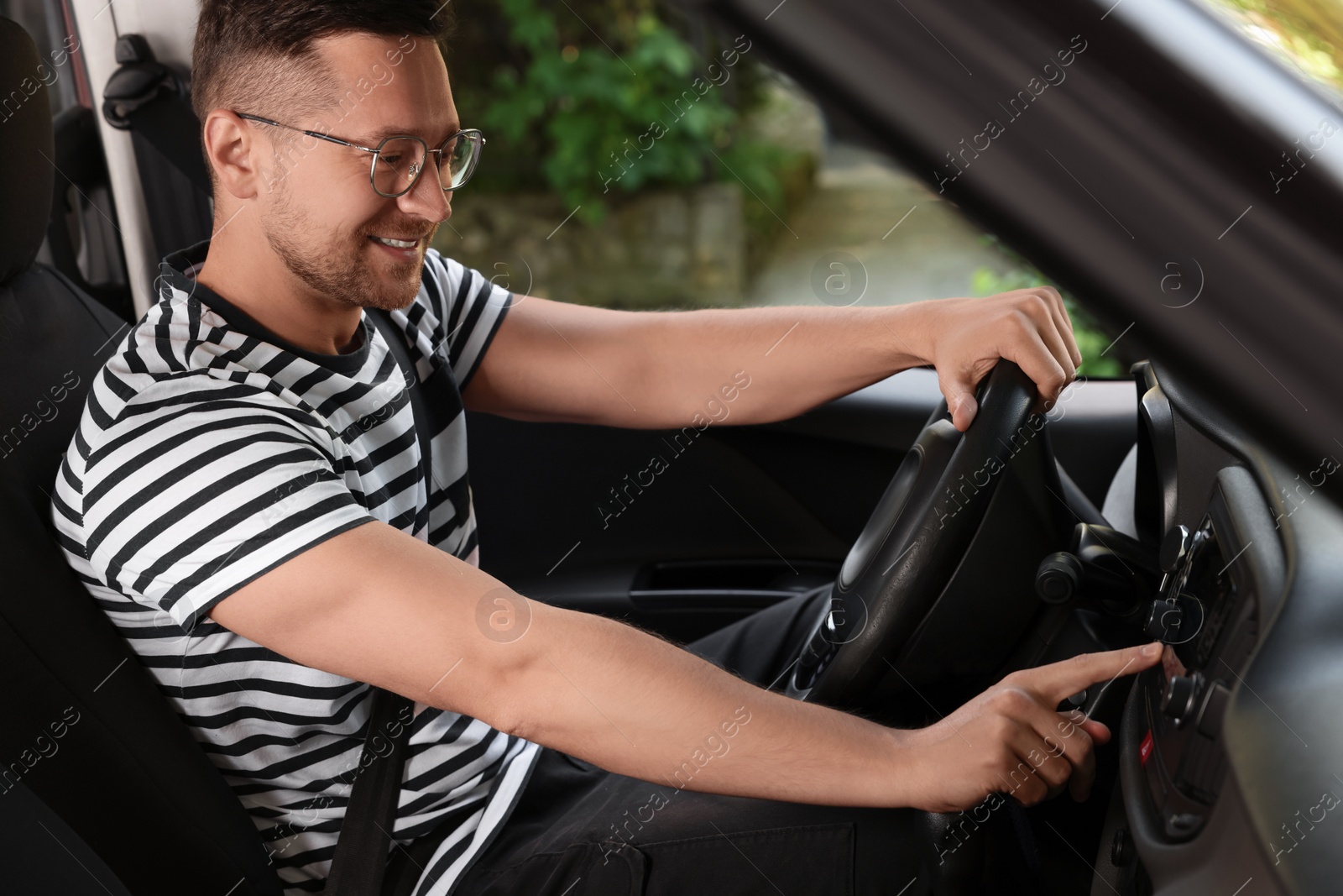 Photo of Choosing favorite radio. Handsome man pressing button on vehicle audio in car