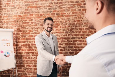 Photo of Office employees shaking hands during meeting at work