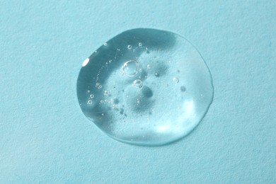 Photo of Sample of cosmetic serum on light blue background, above view