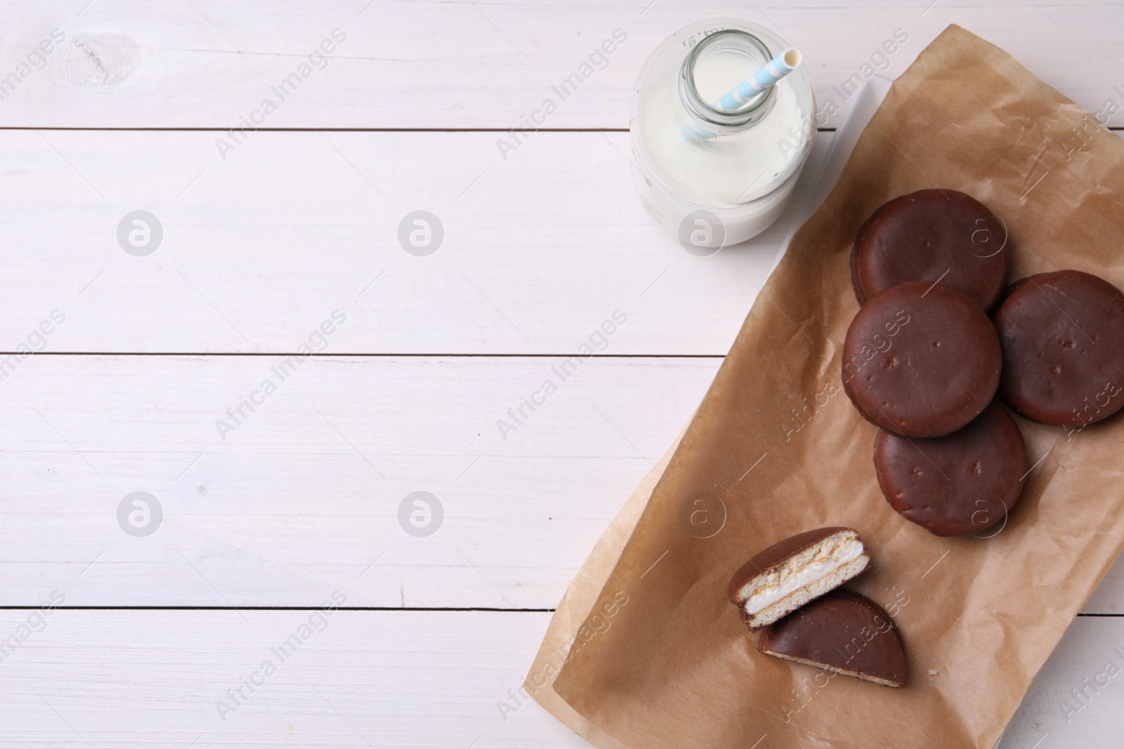 Photo of Tasty choco pies and milk on white wooden table, flat lay. Space for text