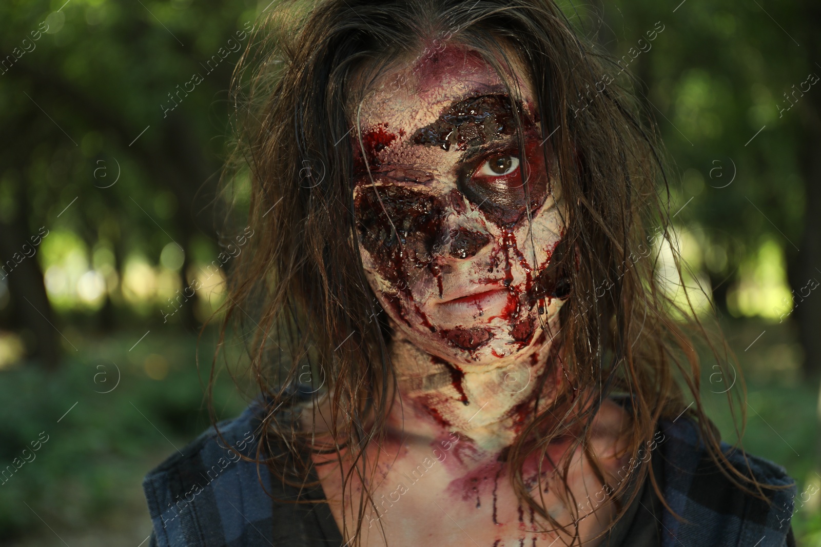 Photo of Scary zombie with bloody face outdoors, closeup. Halloween monster