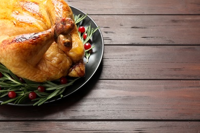 Photo of Delicious cooked turkey served on wooden table, closeup with space for text. Thanksgiving Day celebration