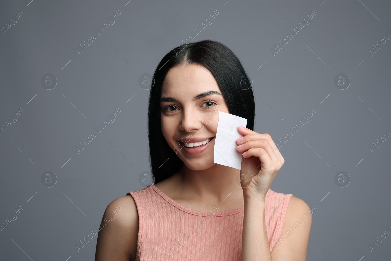 Photo of Beautiful woman using mattifying wipe on grey background