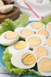 Photo of Fresh hard boiled eggs and lettuce on white wooden table